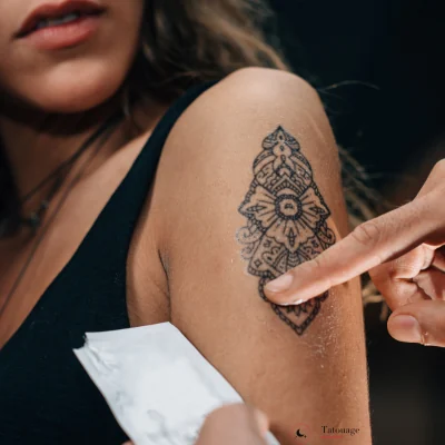 Tatouage semi-permanent ornemental sur le bras d'une femme, motif dont le prix dépend de la taille