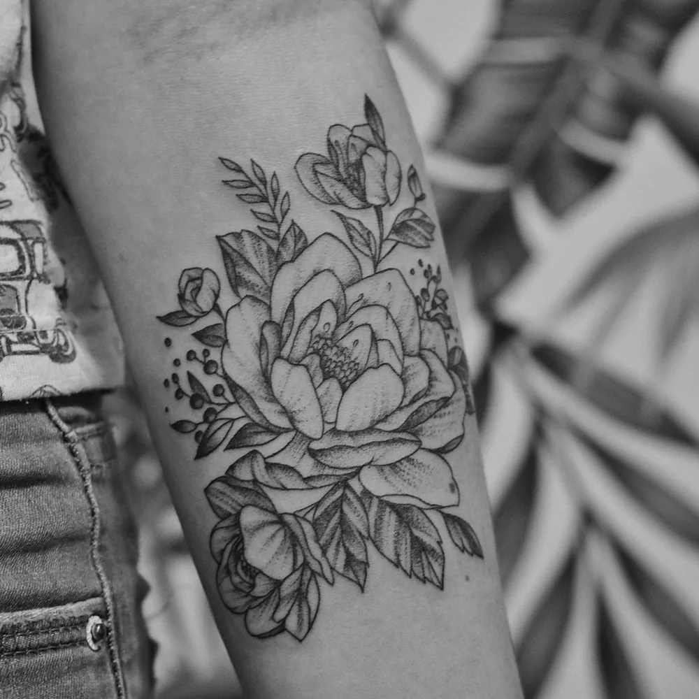 Tatouage éphémère fleur en trait fin sur l'avant-bras Tatouage éphémère fleur en trait fin sur l'avant-bras d'une femme, motif de pivoine et de feuillage